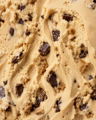 Macro close-up of tan cookie dough gelato studded with dark chocolate chunks and dough pieces