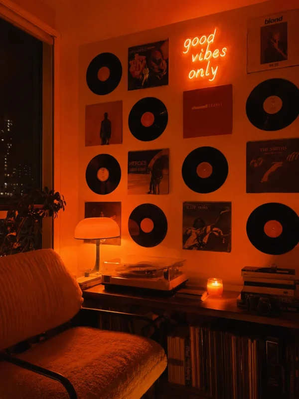 Cosy influencer lounge lit in warm amber with a grid of vinyl records on the wall