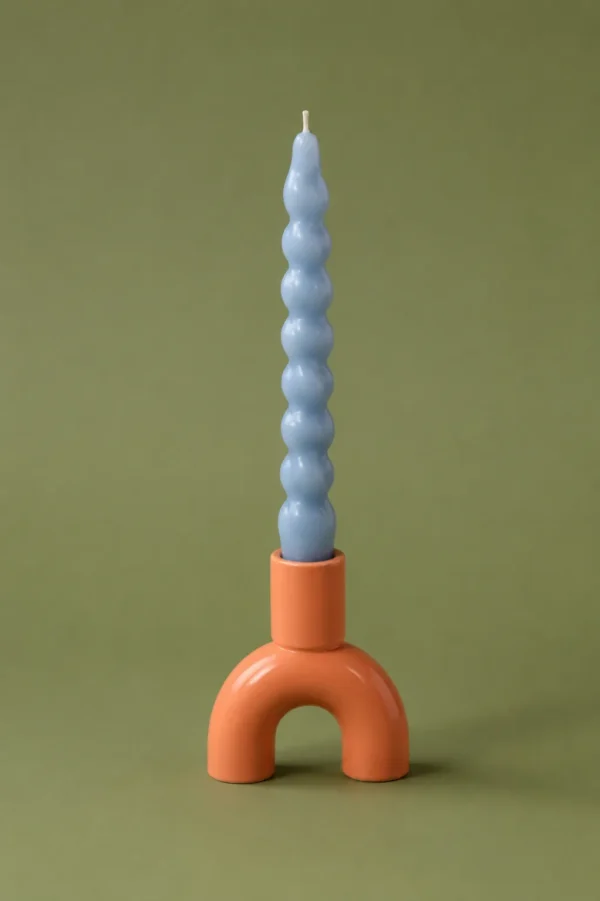 Pale blue spiral taper candle standing in a terracotta arch holder on an olive background