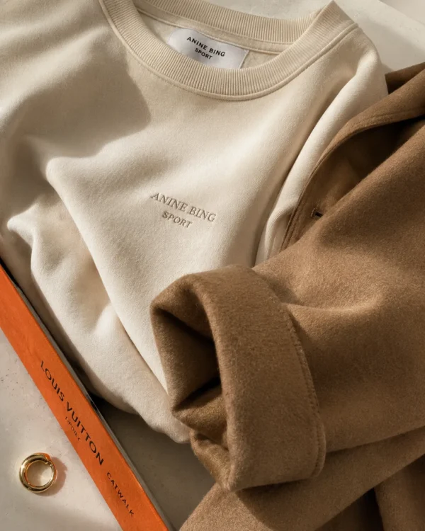 Folded beige sweatshirt and knitwear styled as a soft neutral flatlay detail