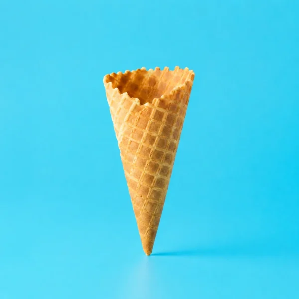 Empty waffle ice cream cone standing upright against a sky-blue background