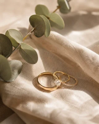 Two gold wedding rings resting on linen beside a sprig of eucalyptus, a Tuscan wedding detail