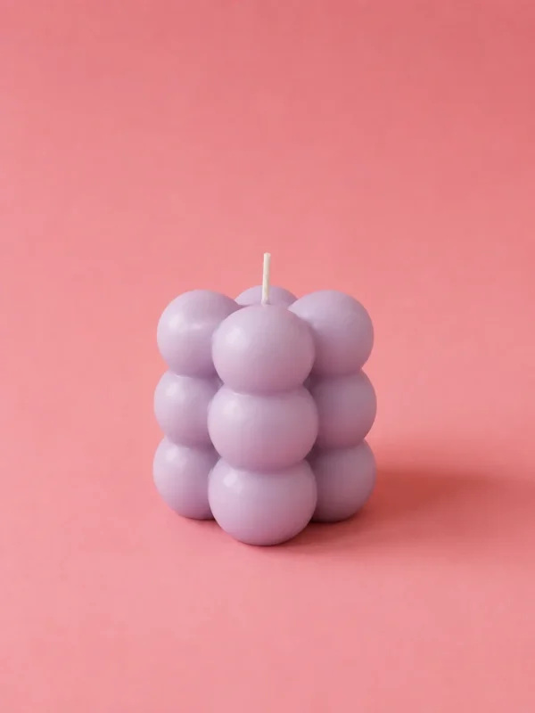 Lilac bubble cube candle made of stacked spheres on a pink studio background