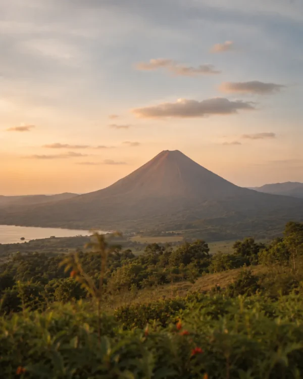 Conical volcano rising over a green valley at sunrise on a travel adventure
