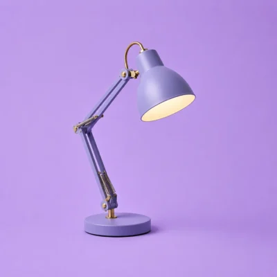 Chrome adjustable desk lamp angled forward on a lavender studio background