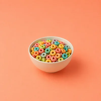 White bowl of rainbow loop cereal centered on a warm coral background