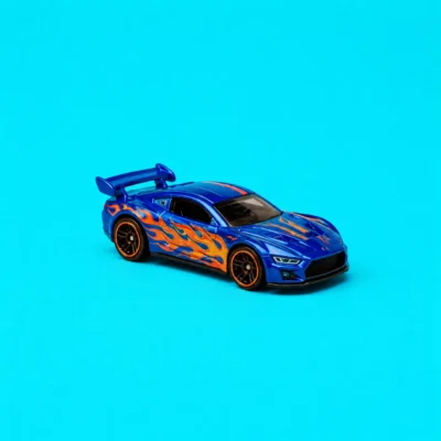 Blue toy race car shown in profile on a bright cyan studio background